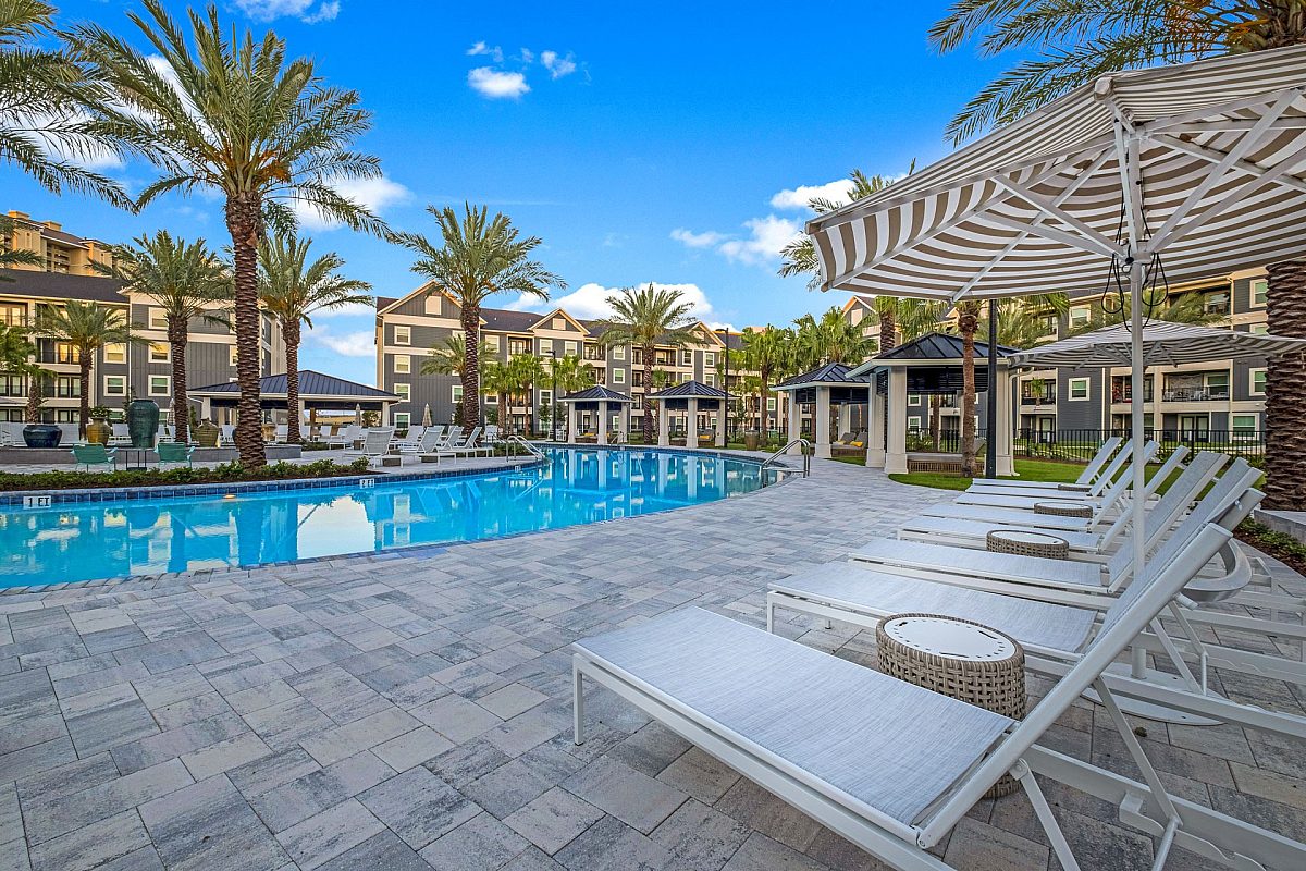 swimming pool area with beach chairs and uymbrella inside an apartment complex