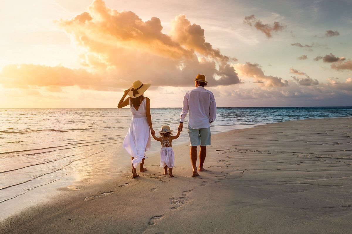 Couple with child walking down the beach.
