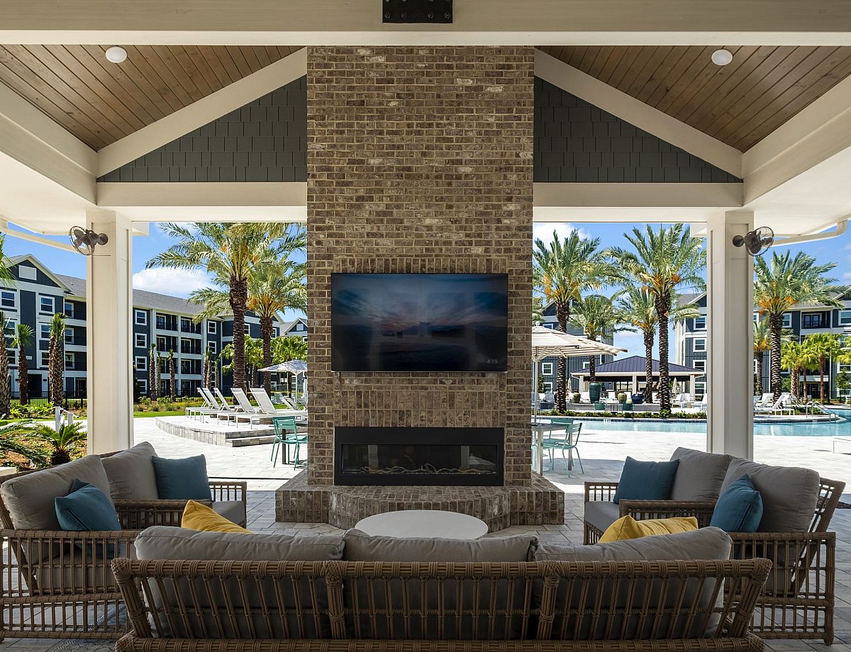 fireplace with tv and sofa near a swimming pool